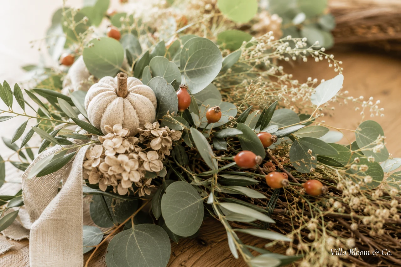 Halb gebundener Herbstkranz auf dem Tisch, daneben Eukalyptus, Beeren und Werkzeug
